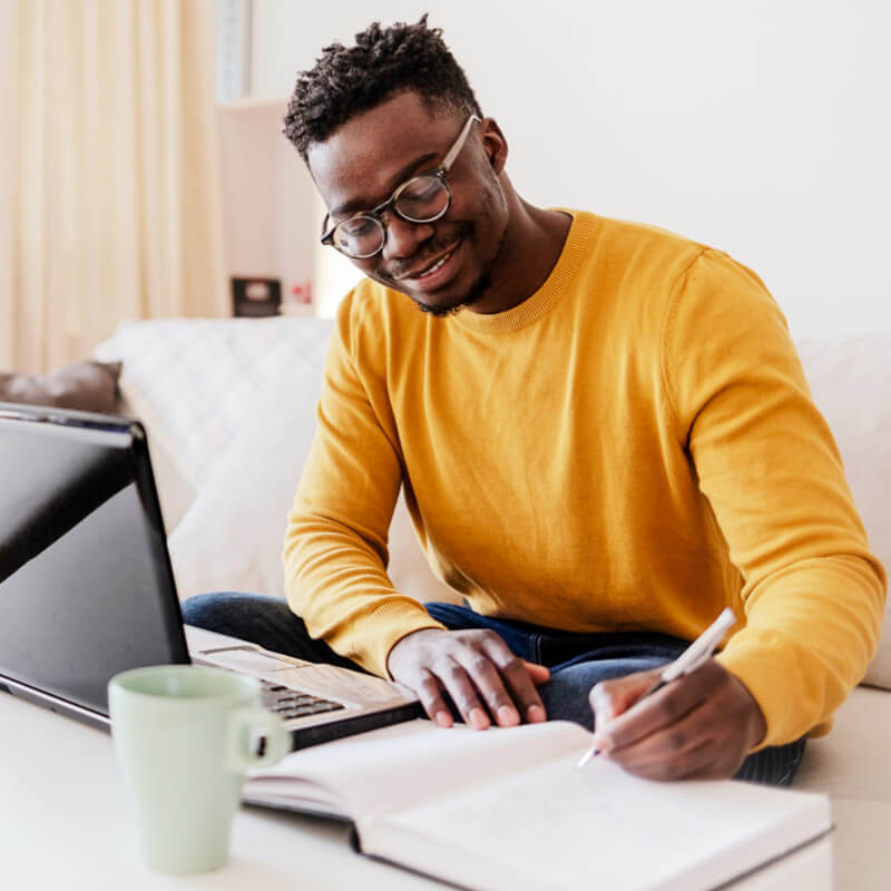 A male student in a yellow jumper doing online eLearning,