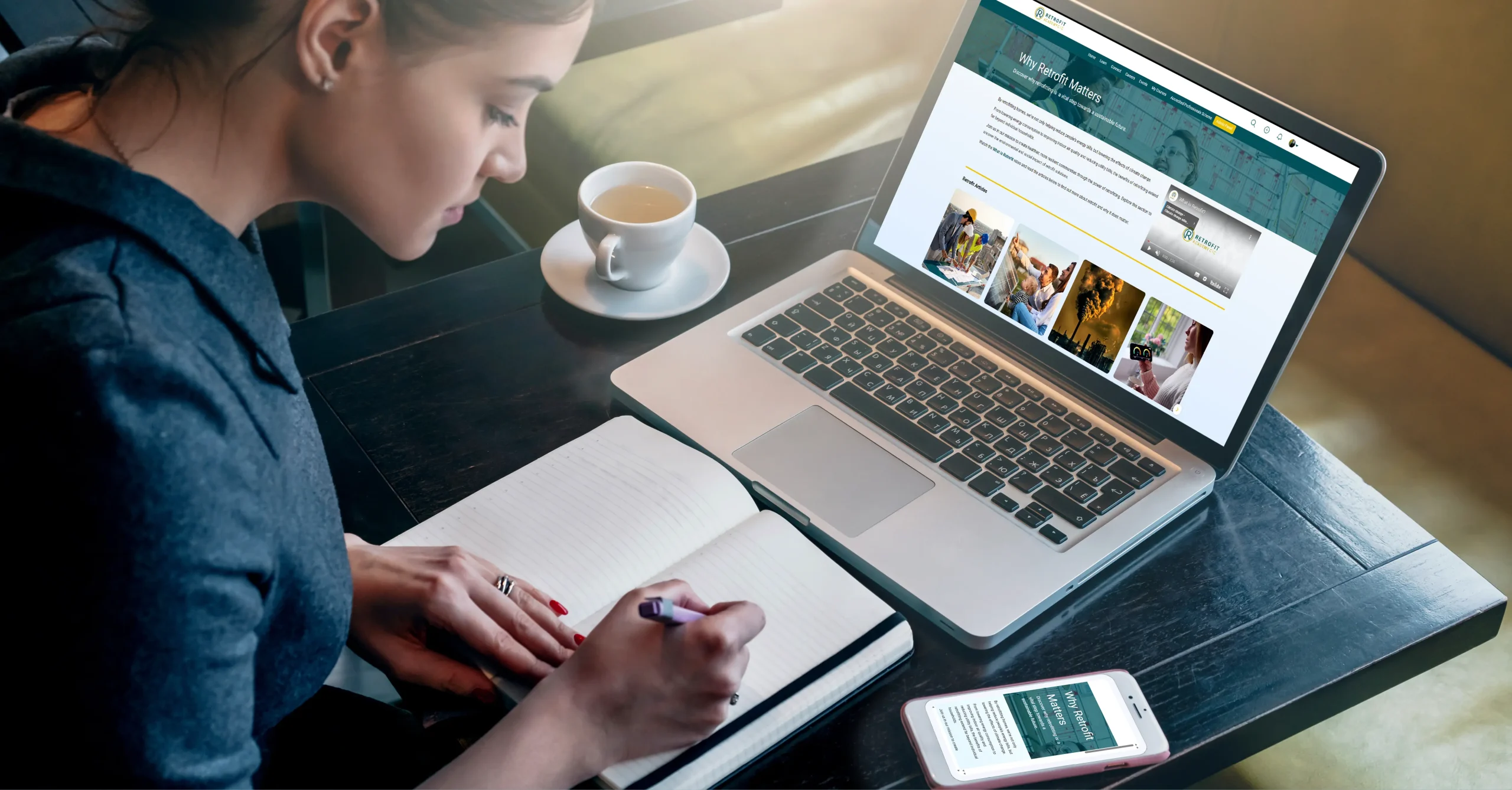 A dark-haired female is sitting at a desk making notes. In front of her, she has open The Retrofit Academy Hub's CPD learning assets, on both desktop and mobile.