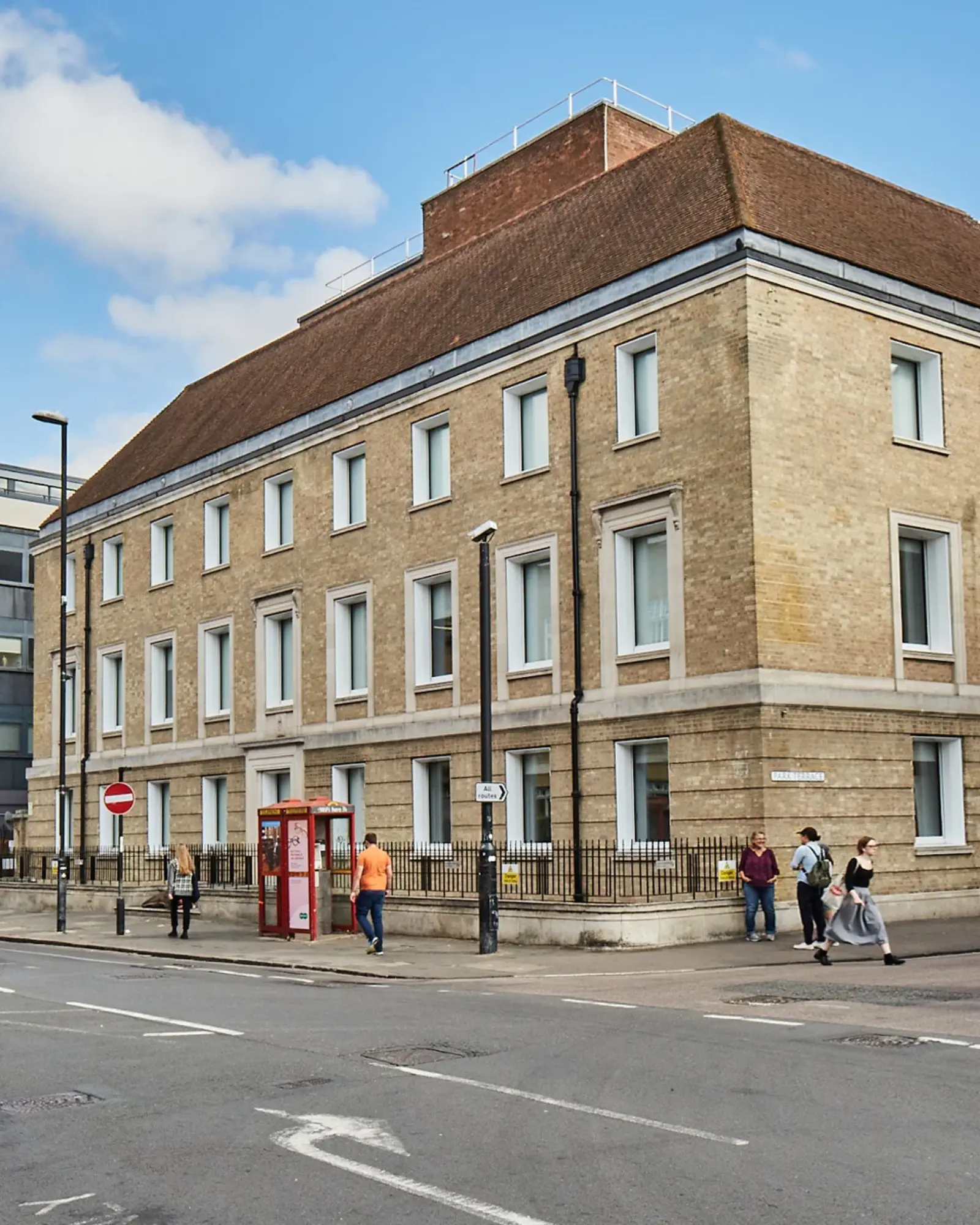 The Entopia Building in Cambridge - an example of Non Domestic Retrofit requirements. Image shows a large building on a corner junction, with yellow bricks and a brown roof.